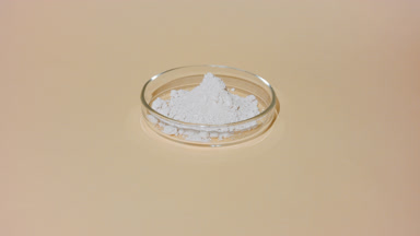 Arc Shot of Beige Powder in Glass Petri Dish