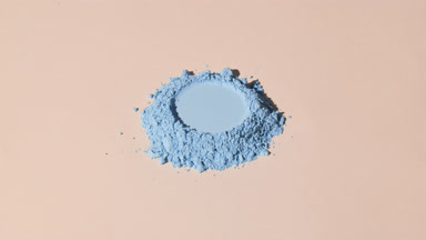Arc Capture of Soft Blue Powder with Imprint on Beige Backdrop