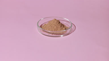 Wide Shot of Brown Powder in Petri Dish on Pale Pink