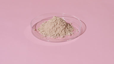 Beige Powder in Petri Dish on Pastel Pink Background