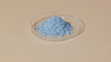 Heap of Blue Powder in Petri Dish on Beige Canvas