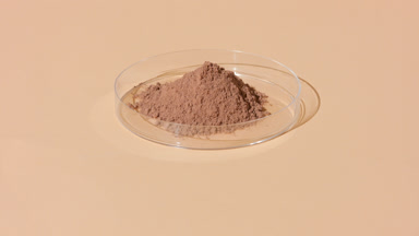 Shifting Shadows on Brown Powder in Transparent Dish