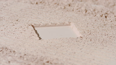 Beige Powder Surface with Square Imprint and Shifting Shadows