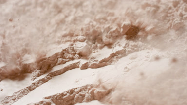 Air Stream Reveals Surface Ridges in Beige Powder
