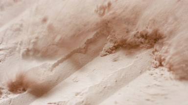 Damaged Beige Powder Layer Revealed in Slow-Motion Close-Up