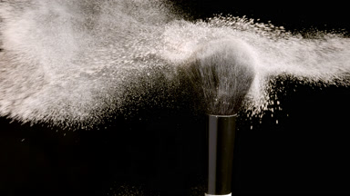 Dynamic Close-Up of Brush Flicking Beige Powder on Black
