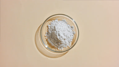 Top-Down View of White Powder in Petri Dish on Beige Surface