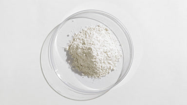 White Powder in Petri Dish on Light Grey Surface with Light