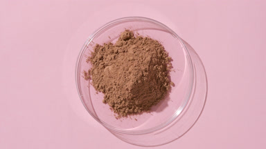 Brown Fine Powder in Petri Dish on Pastel Pink Canvas