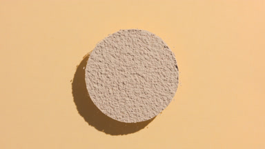 Circular Beige Powder with Shadow on Tan Background