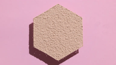 Hexagonal Beige Powder Casting Shadows on Pink Background