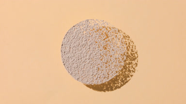 Beige Powder Circle Casting Shadows on Tan Background