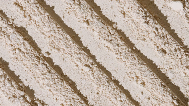 Beige Powder Surface with Parallel Scraping Patterns