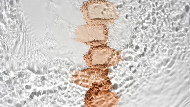 Water Flowing Over Beige Powder Heaps on Grey Backdrop