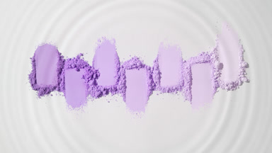 The droplet forms intricate patterns in the violet powder
