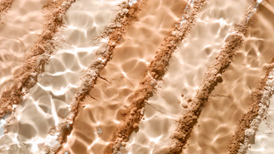 High-Magnification Water Splash Over Beige Powder Surface