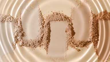 Close-Up of Droplet Expanding Circles Over Beige Powder
