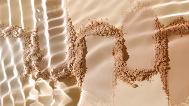 Extreme Close-Up of Water Stream Over Beige Powder