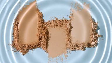 Macro Shot of Droplet Over Skintone Powder on Pale Blue