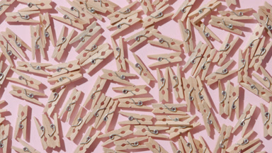 Illuminated Clothespins on Pink Surface with Shifting Shadows