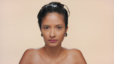 Latin woman with smooth light brown skin gazes at camera