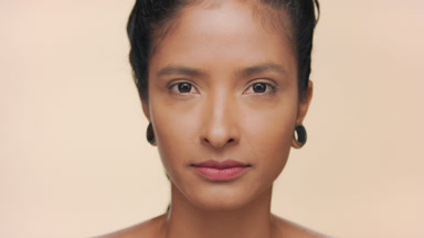 Woman with moisturized light brown skin opens eyes for camera