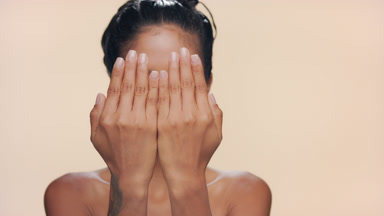 Argentine woman with caramel smooth skin covers face smiling