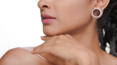 Hispanic woman strokes jawline showing revitalized skin