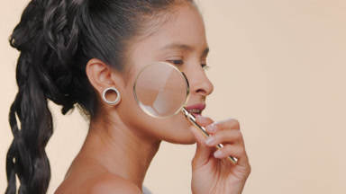 Argentinian woman with smooth light brown skin holds magnifier