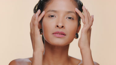 Latin woman smooth skin strokes forehead tan background