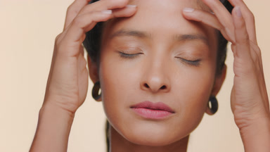Argentine woman smooth light brown skin strokes forehead tan bg