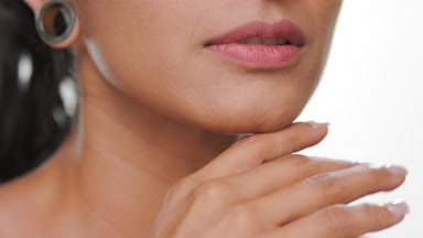 Argentinian woman strokes jawline showing smooth skin