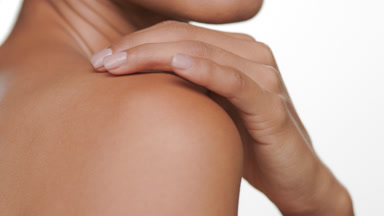 Argentine bronzed woman strokes shoulder reflecting soft skin