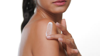 Latin american woman applies moisturizing cream on shoulder