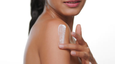 Latin woman with bronzed skin apply nourishing cream on shoulder