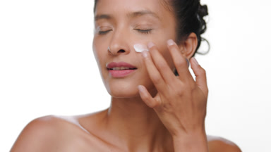 South american woman applies cream on cheek light brown skin