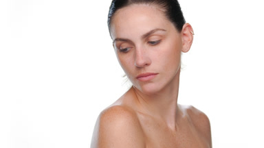 Freckled light-skinned latina looks over shoulder on light bg