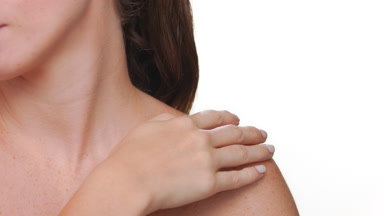 Spanish woman with fair skin freckles strokes clavicles on white
