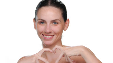 Young fair-skinned latina making heart gesture on white backdrop