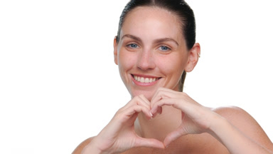 Fair-skinned latina with freckles form heart with hands on white