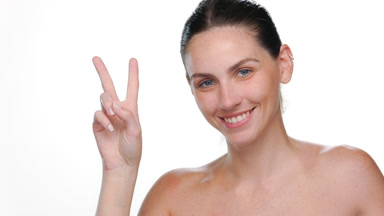 Light-skinned latina with freckles shows peace sign on white bg