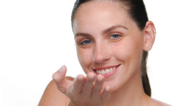 Young fair-skinned latina with freckles blows kiss on light bg