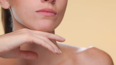 Young woman with freckles strokes jawline shows firm skin