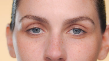 Latina with fair skin and blue eyes looks at camera on beige