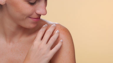 Caucasian latina with freckles caresses shoulder healthy skin