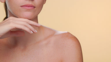 Hispanic woman with fair skin freckles strokes jawline firm skin