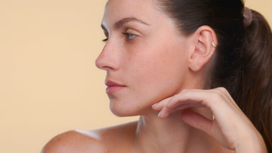 Spanish woman with fair skin freckles strokes jawline fresh skin