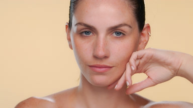 Fair-skinned blue-eyed model strokes jawline well hydrated skin