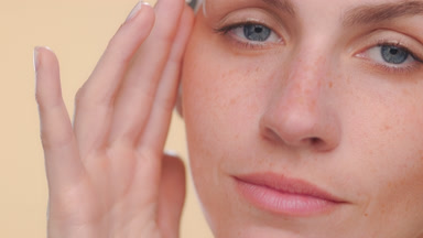 Fair-skinned latina with freckles strokes face soft skin
