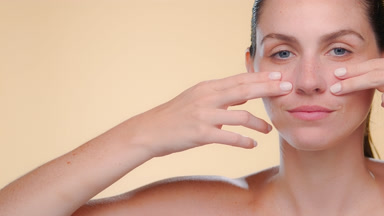Light-skinned freckled latina strokes under-eye elastic skin